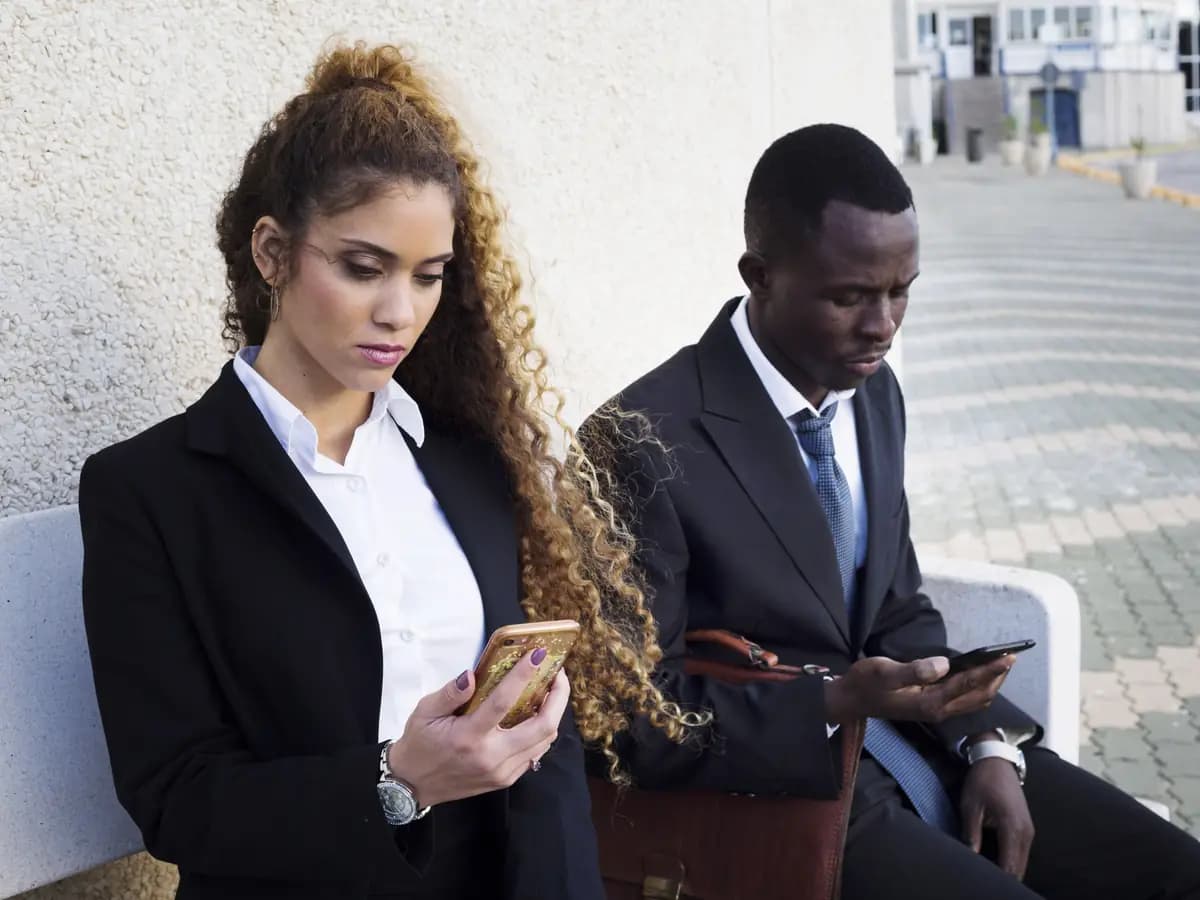 Two professionals checking their phones outdoors